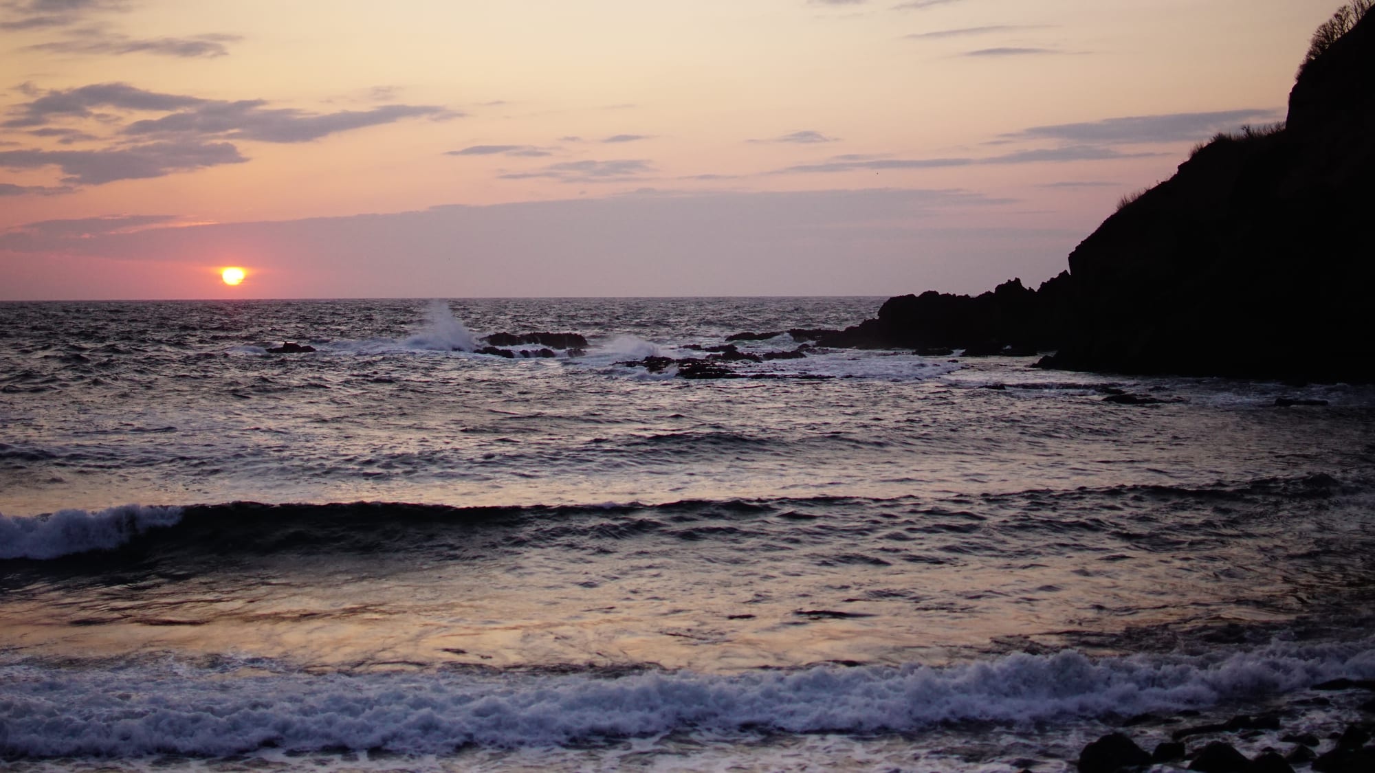 Sunset over a rocky coastline with waves