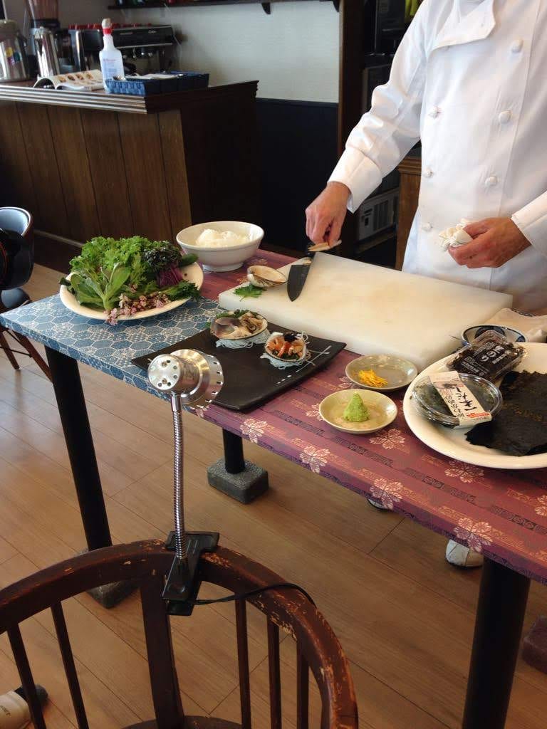 A chef preparing shellfish at a table set for service