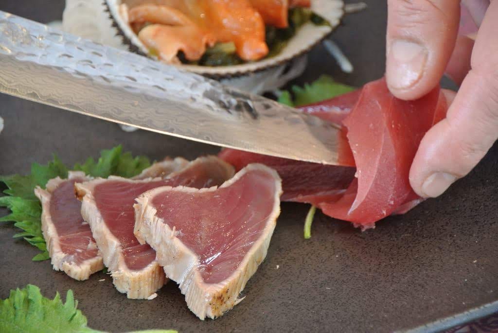 A chef slicing fresh tuna sashimi